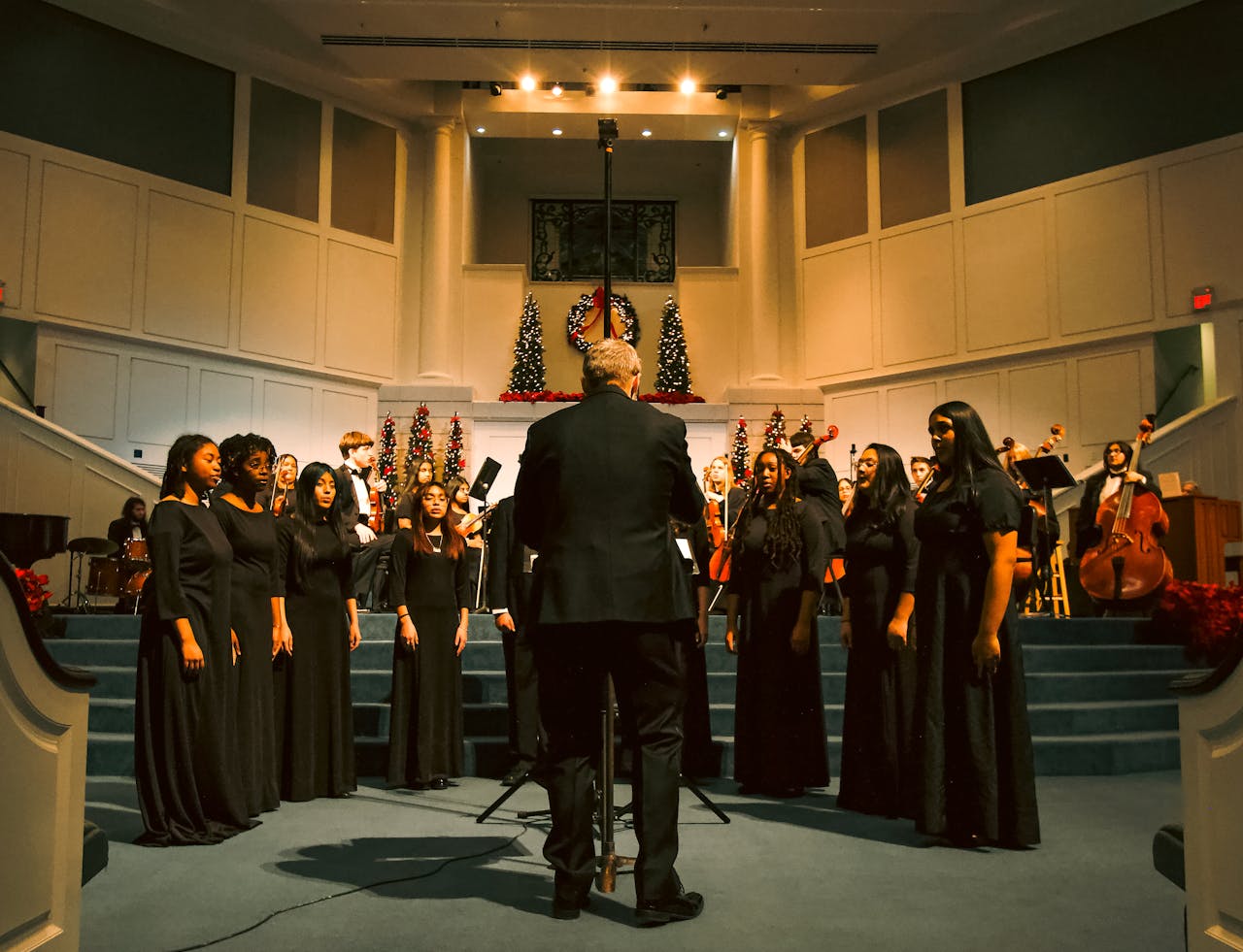 services-03 Choir in black attire sings at a church with Christmas decorations.