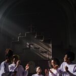 Group of people singing and dancing in a sunlit church setting, expressing faith and joy.